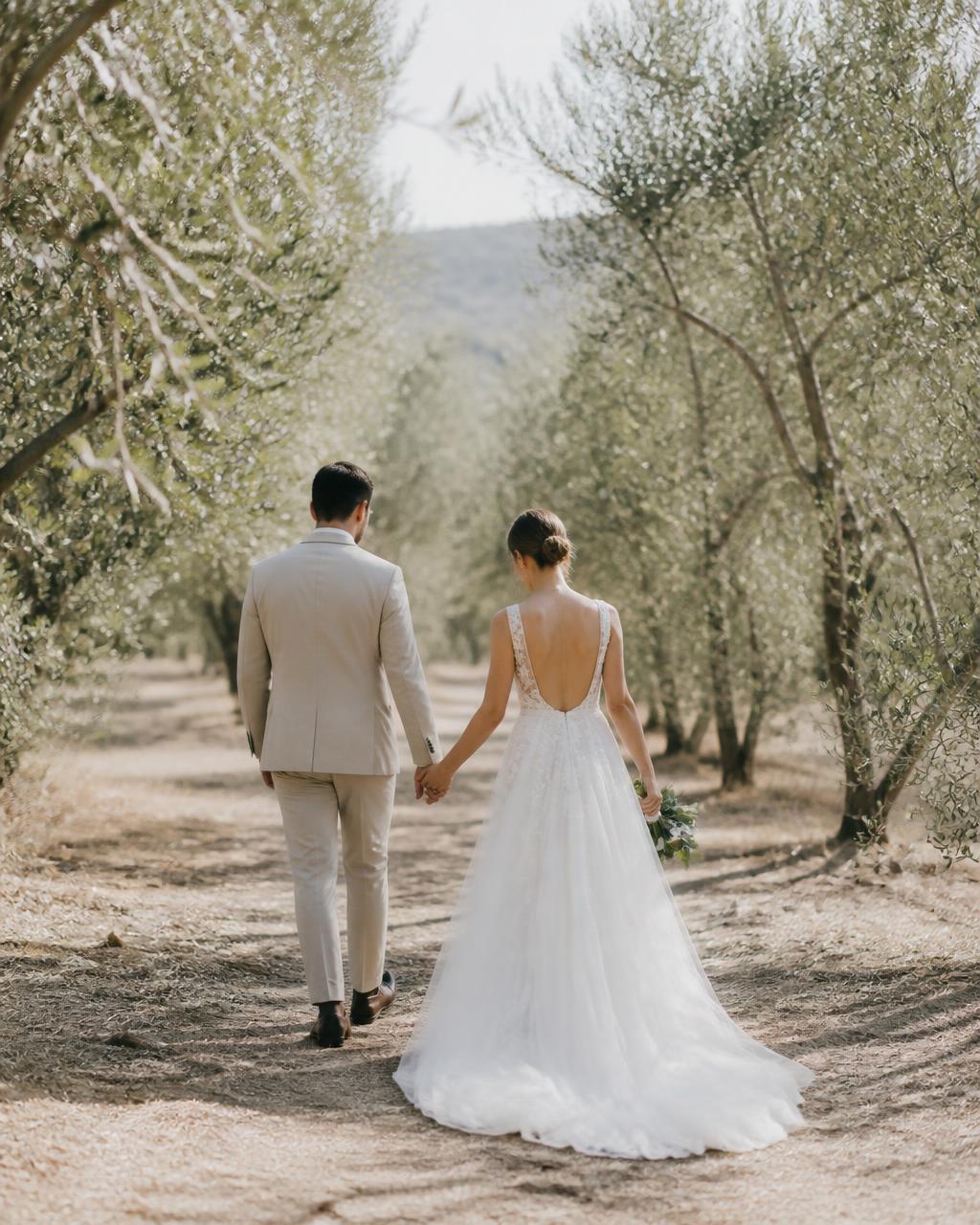 Los novios caminando de la mano por un olivar